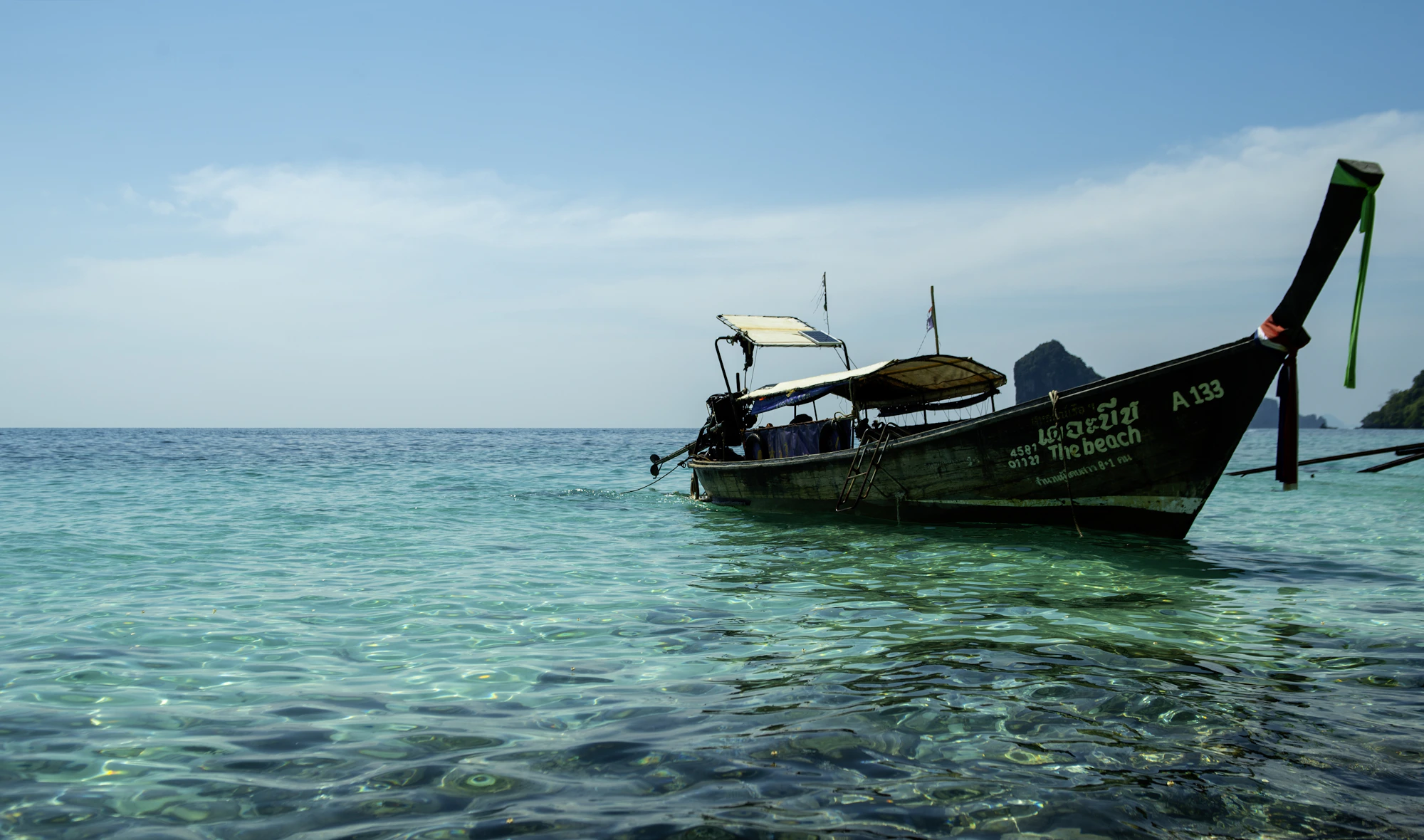 A longtail boat on clear water beside Thailand’s coast